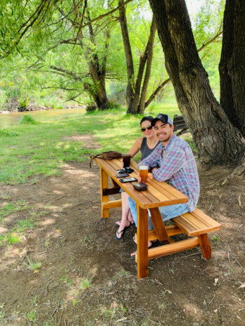 Guest relaxing at a picnic table beside Bear Creek